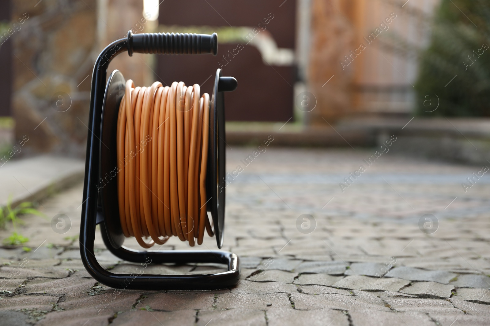 Photo of One extension cord reel on pavement outdoors, space for text