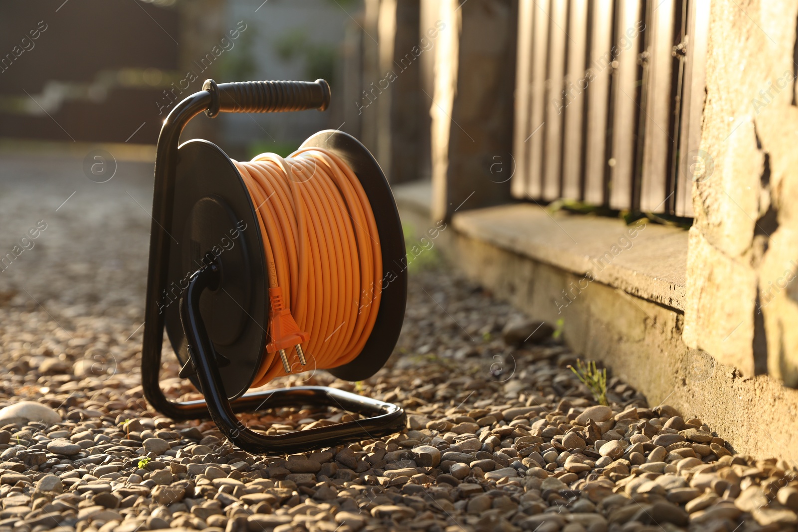 Photo of One extension cord reel on stones outdoors, space for text