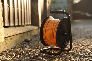 Photo of One extension cord reel on stones outdoors