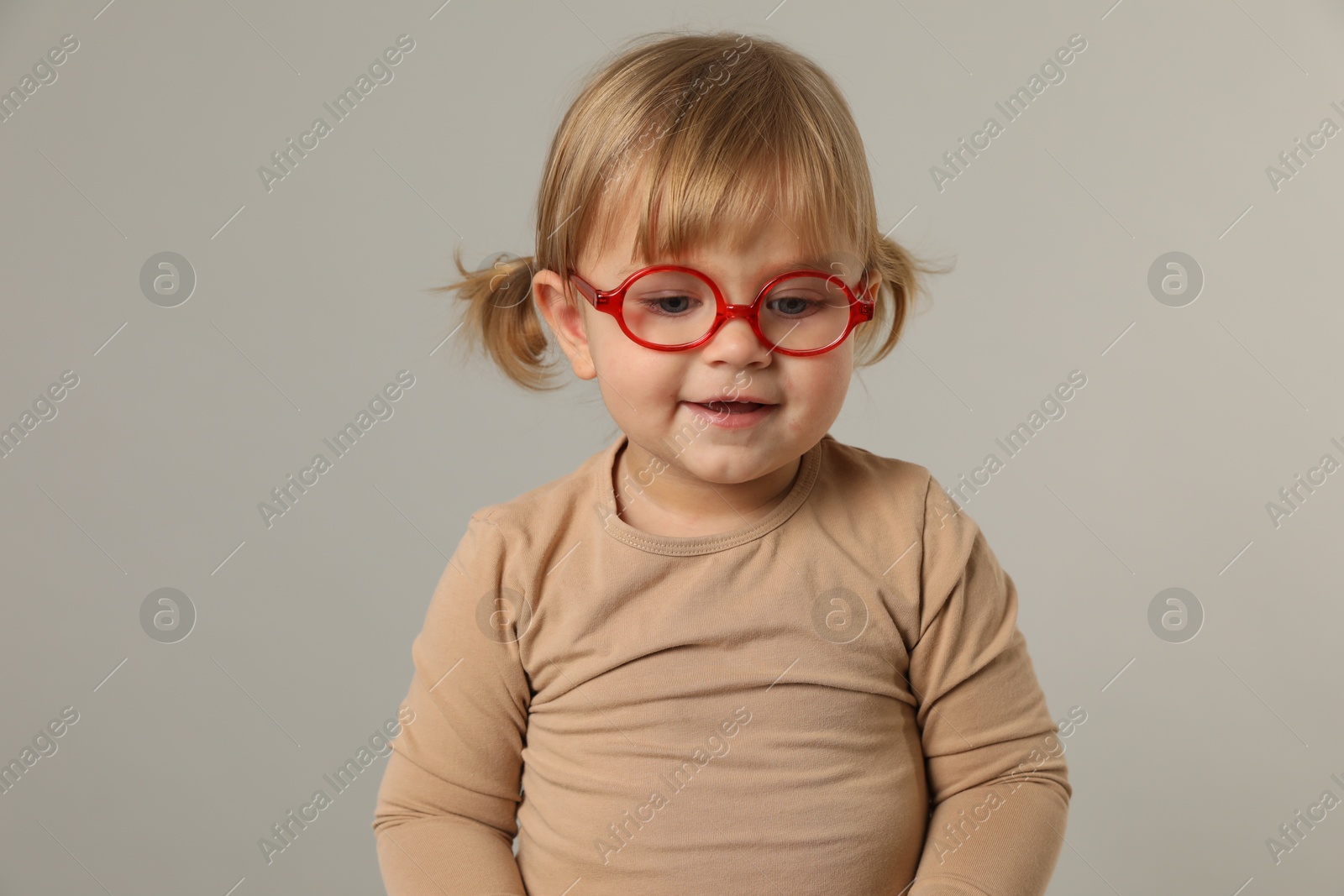 Photo of Cute little girl in glasses on light grey background