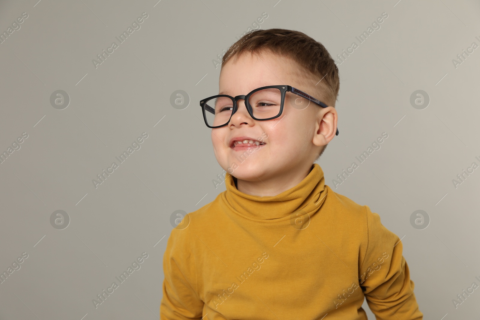 Photo of Cute little boy in glasses on light grey background. Space for text