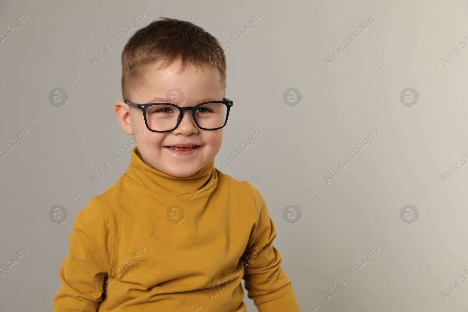 Photo of Cute little boy in glasses on light grey background. Space for text