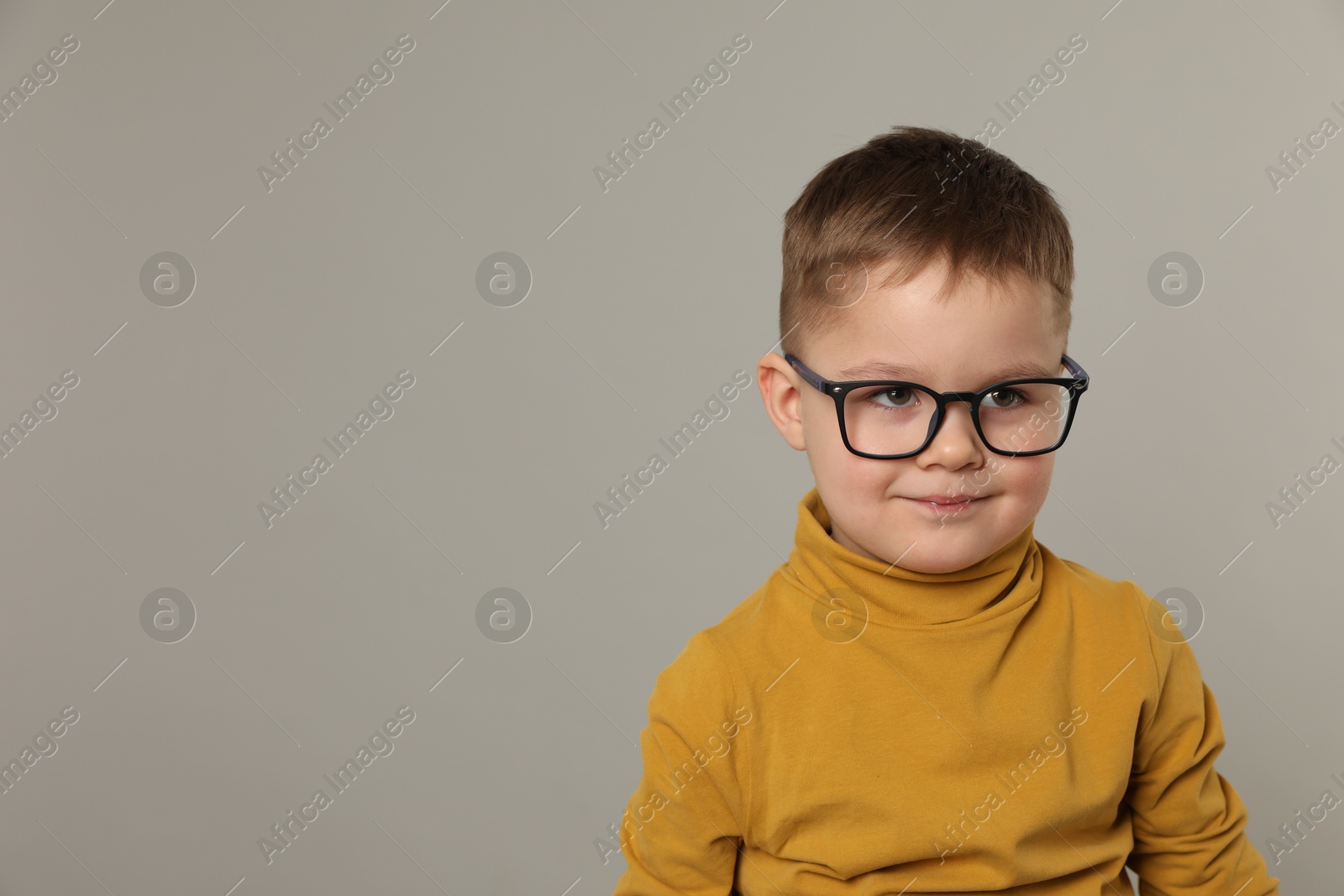 Photo of Cute little boy in glasses on light grey background. Space for text