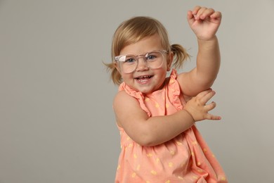 Photo of Cute little girl in glasses on light grey background. Space for text