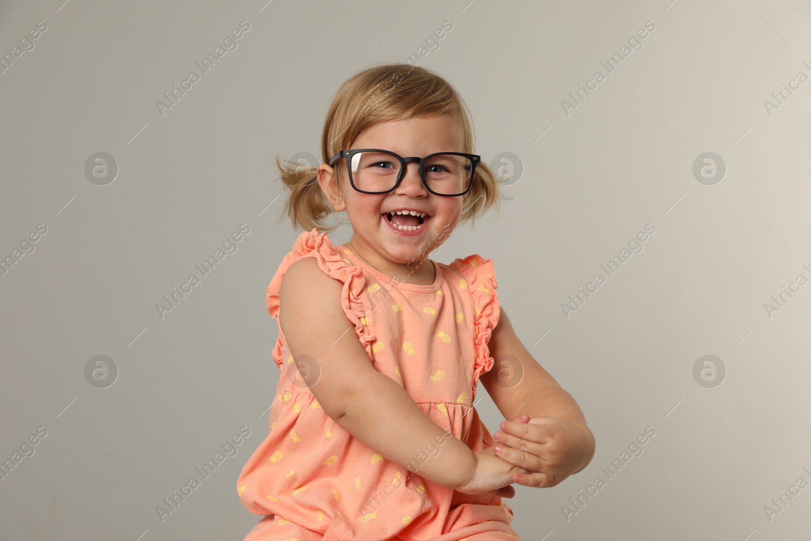 Photo of Cute little girl in glasses on light grey background