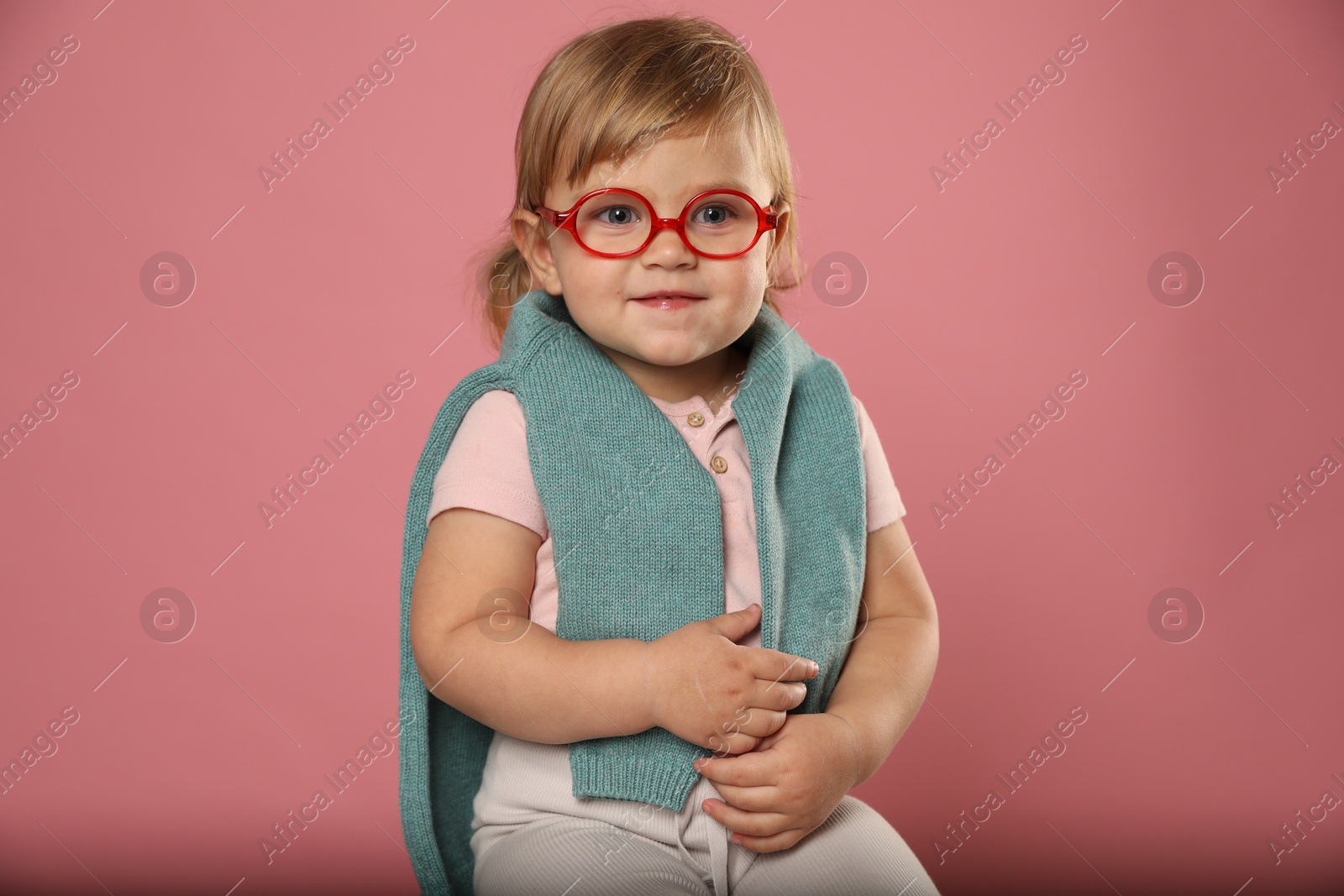 Photo of Cute little girl in glasses on pink background