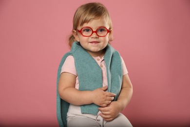 Photo of Cute little girl in glasses on pink background