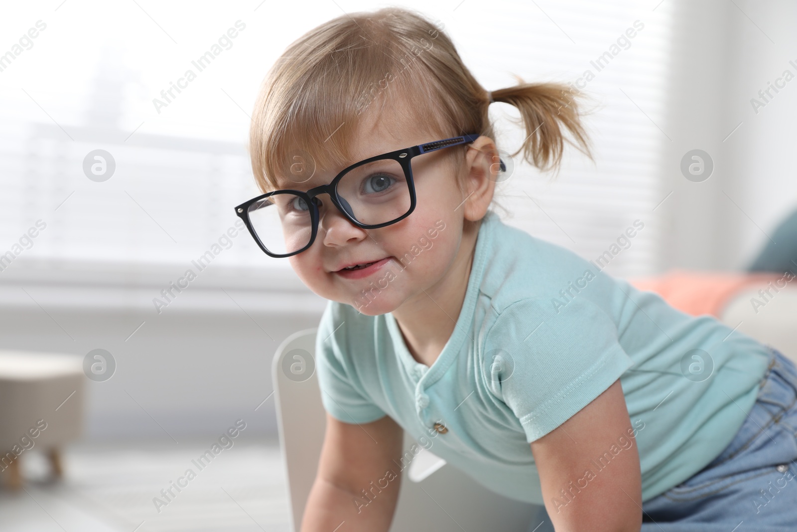 Photo of Cute little girl in glasses at home. Space for text