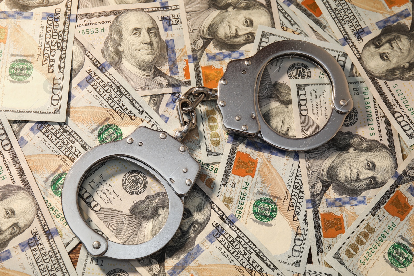 Photo of Handcuffs on pile of dollar banknotes, above view