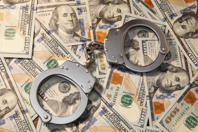 Handcuffs on pile of dollar banknotes, above view