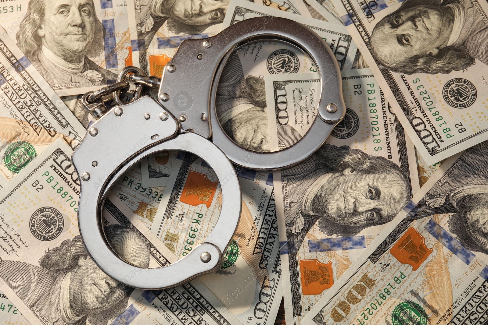 Photo of Handcuffs on pile of dollar banknotes, above view