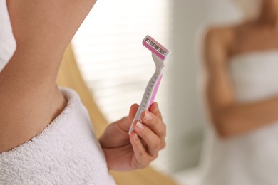 Woman shaving armpit near mirror indoors, closeup. Space for text