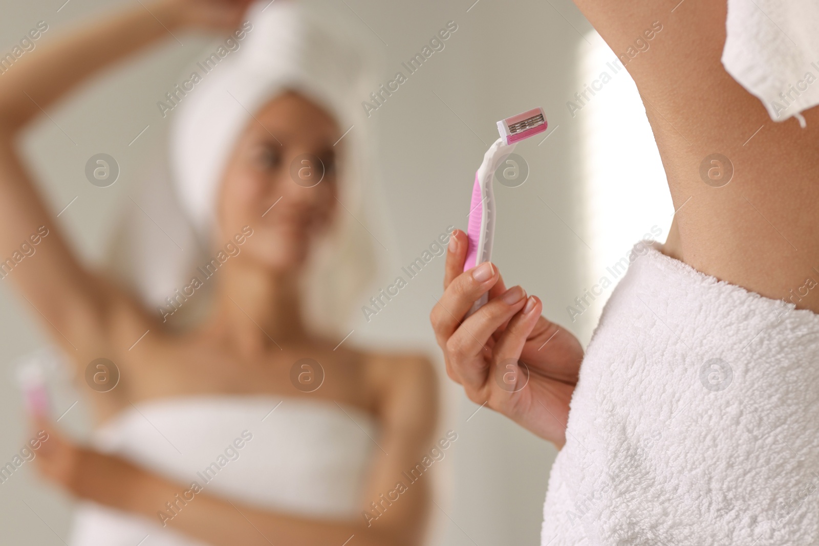 Photo of Woman shaving armpit near mirror indoors, closeup. Space for text