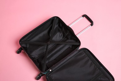 Open empty suitcase on pink background, above view