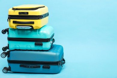 Photo of Stack of different suitcases on light blue background, space for text