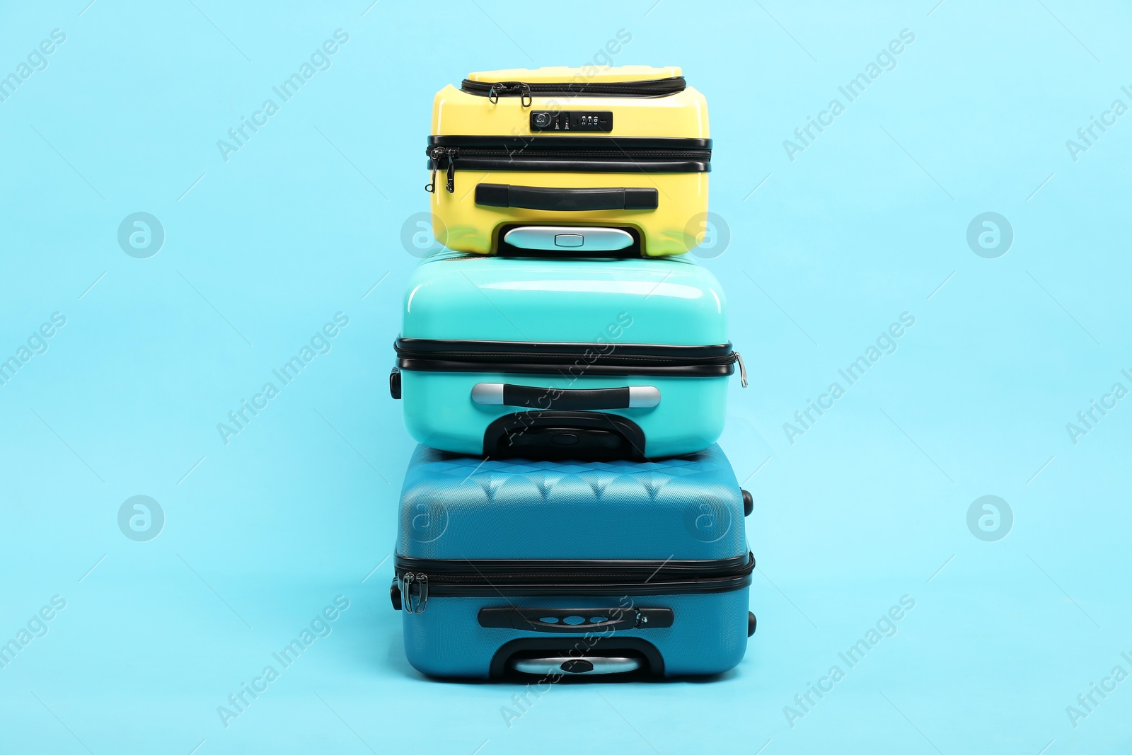 Photo of Stack of different suitcases on light blue background