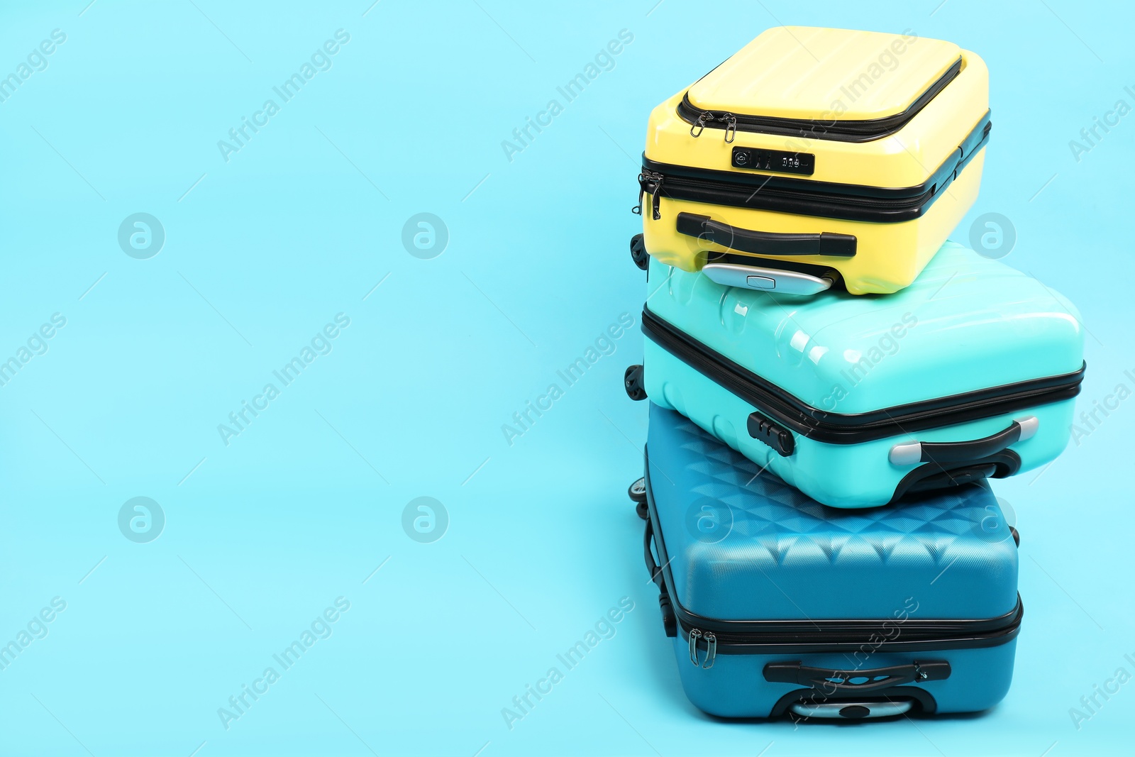 Photo of Stack of different suitcases on light blue background, space for text