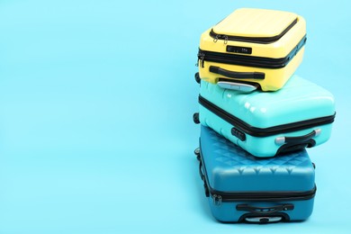 Photo of Stack of different suitcases on light blue background, space for text