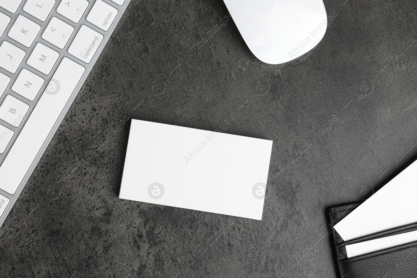 Photo of Leather card holder with blank business cards, mouse and keyboard on grey textured table, flat lay. Mockup for design