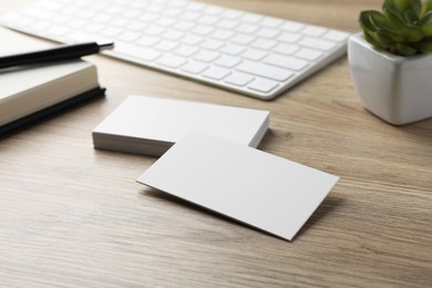 Blank business cards and keyboard on wooden table. Mockup for design