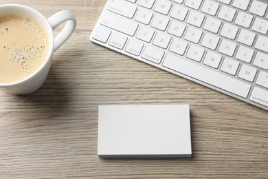 Photo of Blank business cards, coffee and keyboard on wooden table, flat lay. Mockup for design