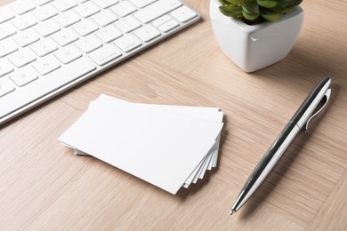 Photo of Blank business cards, pen and keyboard on wooden table. Mockup for design