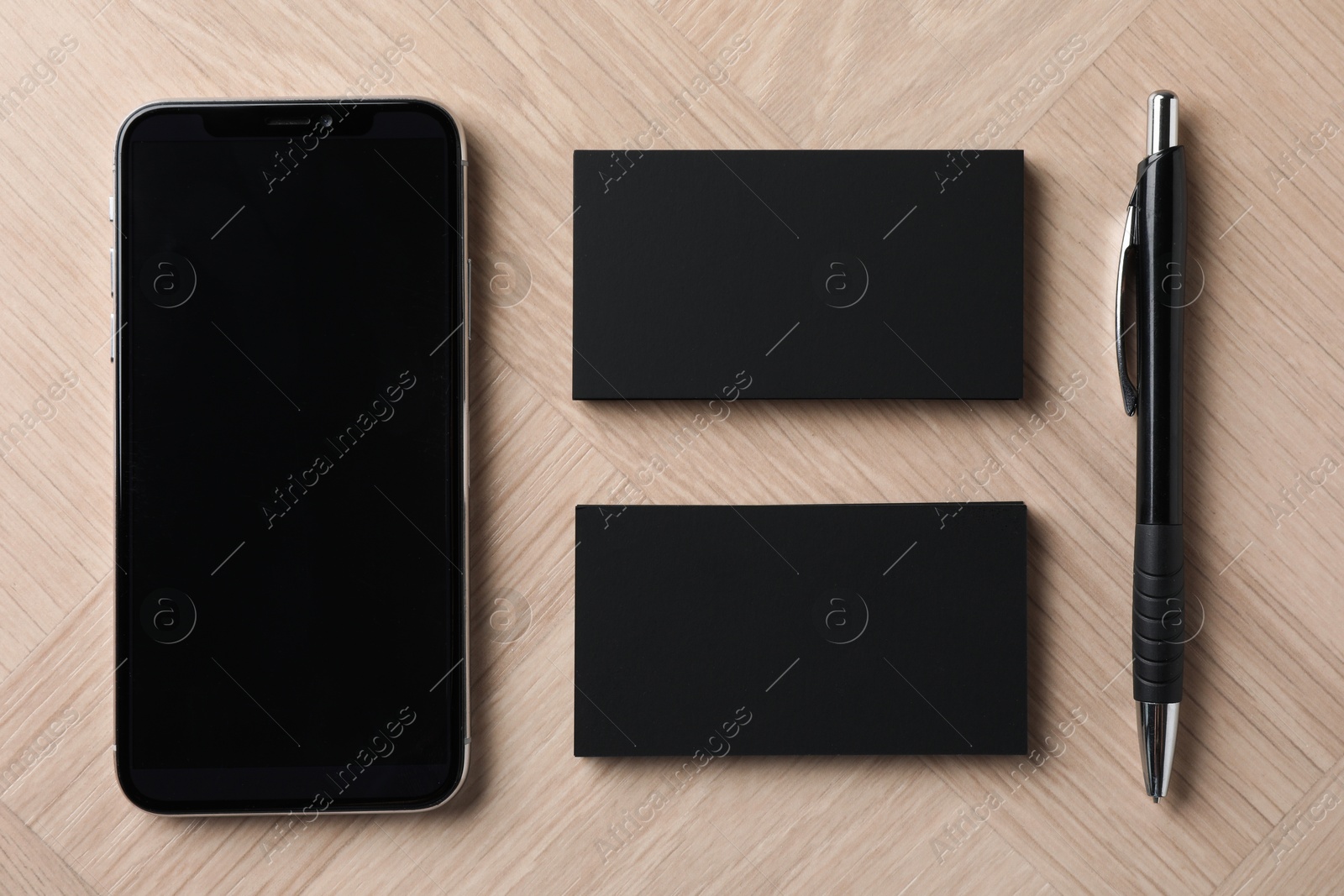 Photo of Blank business cards, pen and smartphone on wooden table, flat lay. Mockup for design