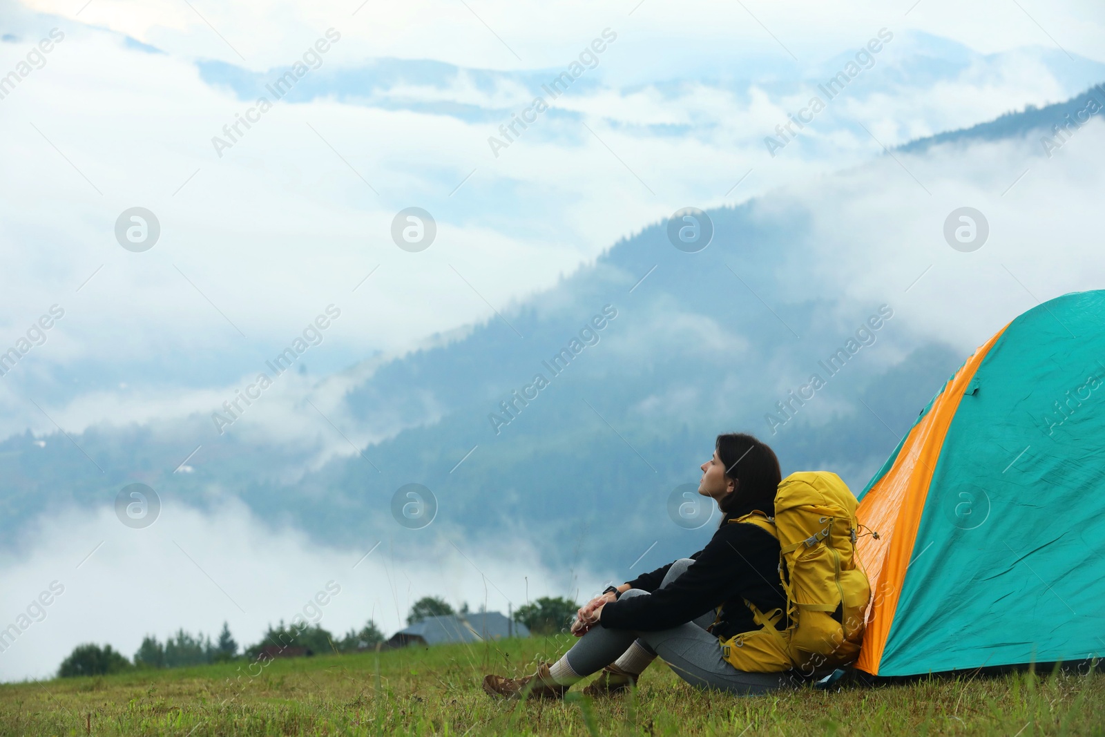 Photo of Young camper with backpack and tent in mountains, space for text