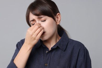 Woman suffering from sinusitis on grey background