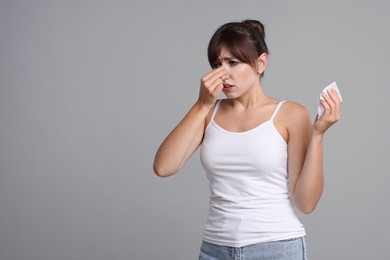 Woman with napkin suffering from sinusitis on grey background. Space for text