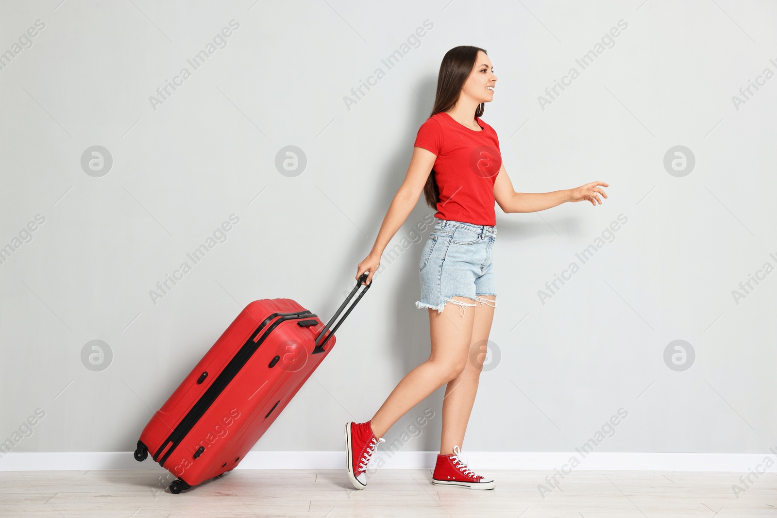 Photo of Happy young woman with suitcase walking indoors