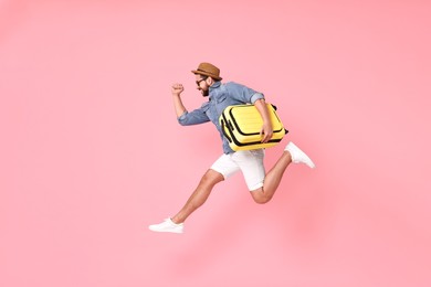 Photo of Happy man in sunglasses with suitcase jumping on pink background