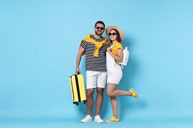 Photo of Happy couple with suitcase on light blue background