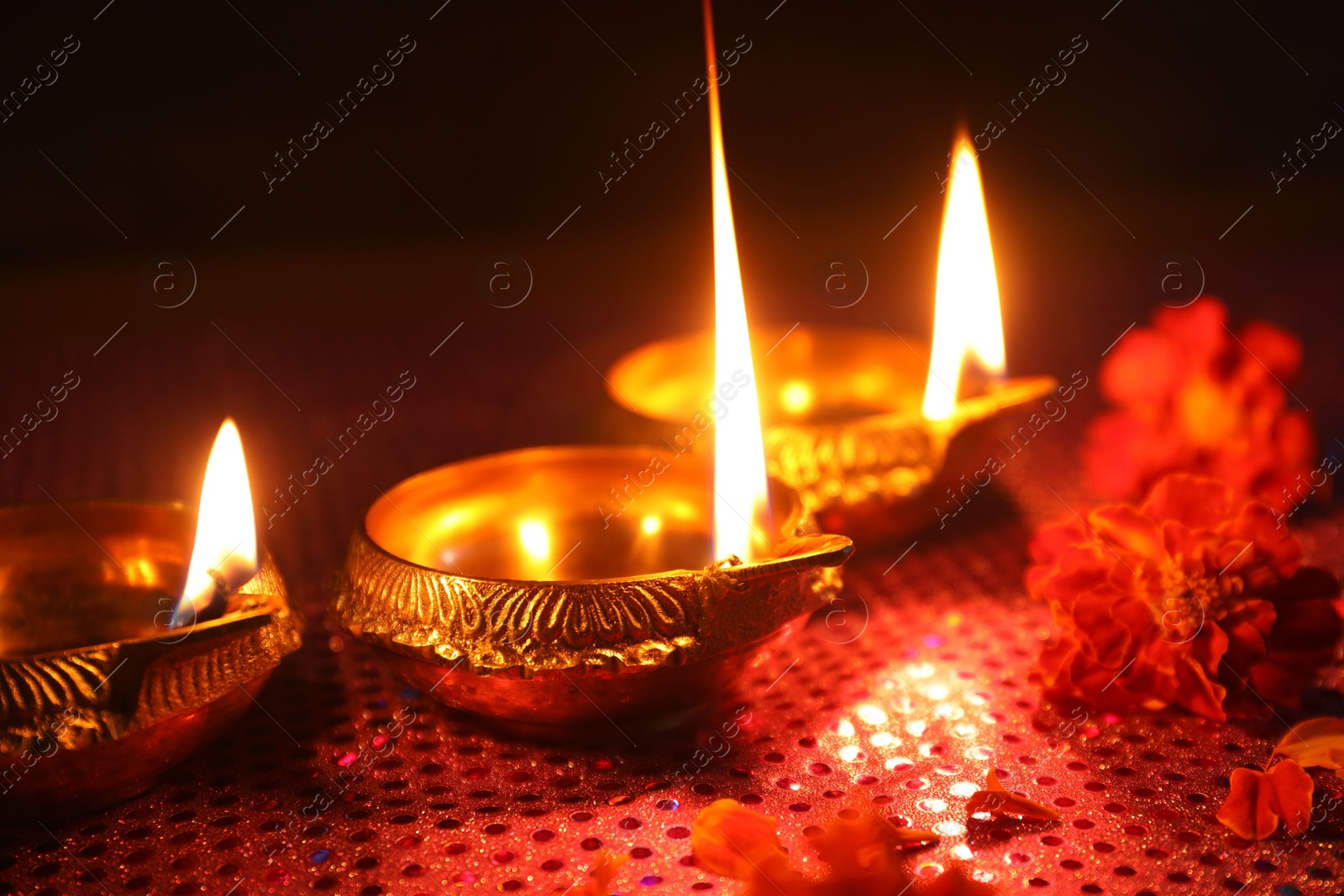 Photo of Diwali celebration. Diya lamps and beautiful flowers on dark background, closeup