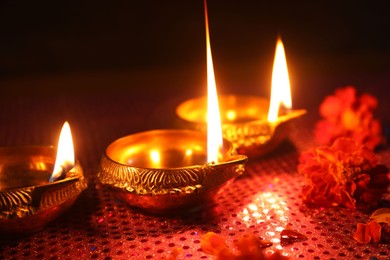 Photo of Diwali celebration. Diya lamps and beautiful flowers on dark background, closeup