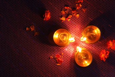 Photo of Diwali celebration. Diya lamps and beautiful flowers on dark background, top view