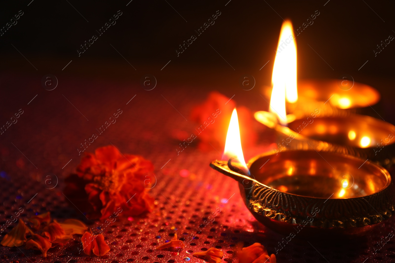 Photo of Diwali celebration. Diya lamps and beautiful flowers on dark background, closeup. Space for text