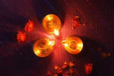 Photo of Diwali celebration. Diya lamps and beautiful flowers on dark background, top view