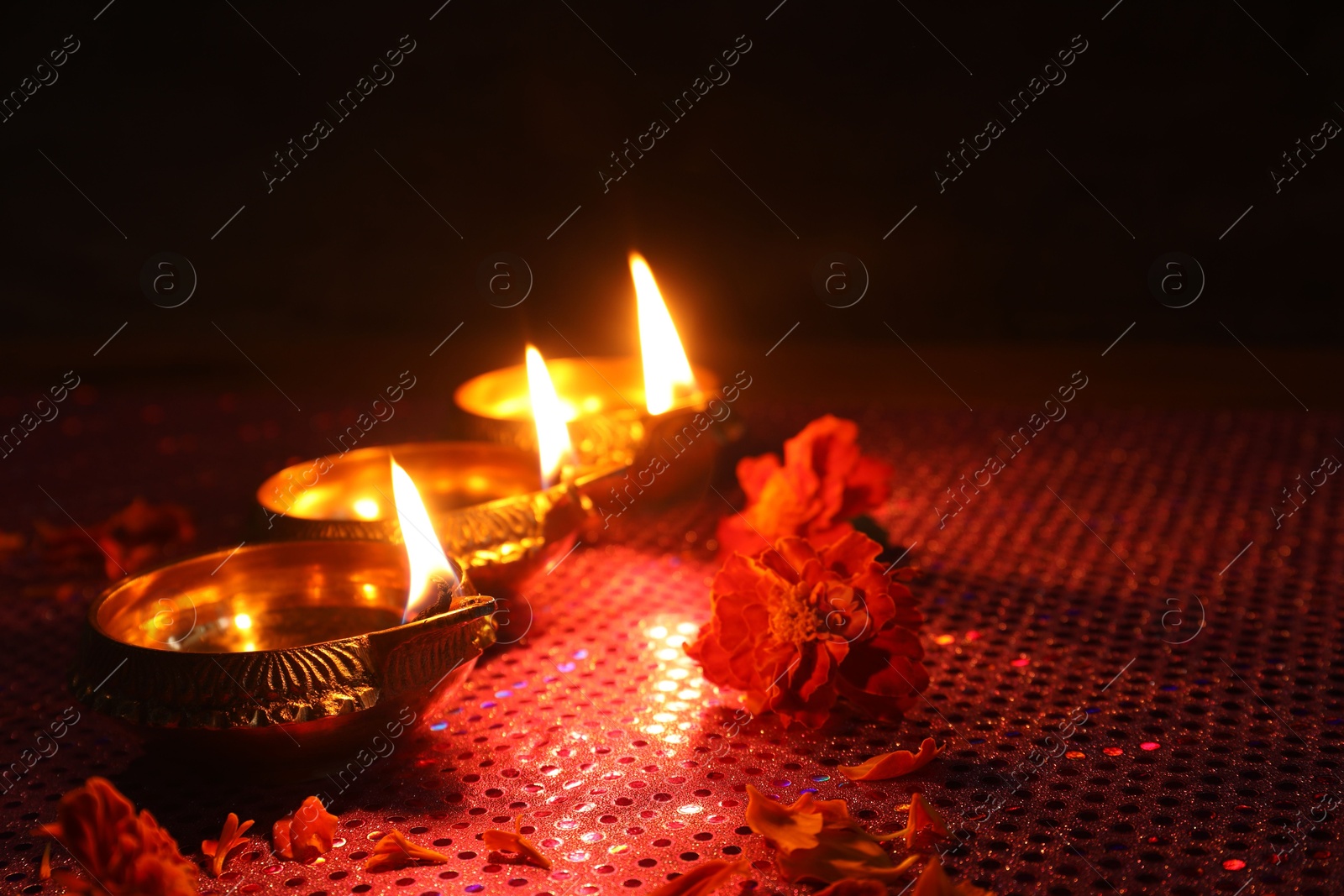 Photo of Diwali celebration. Diya lamps and beautiful flowers on dark background, closeup