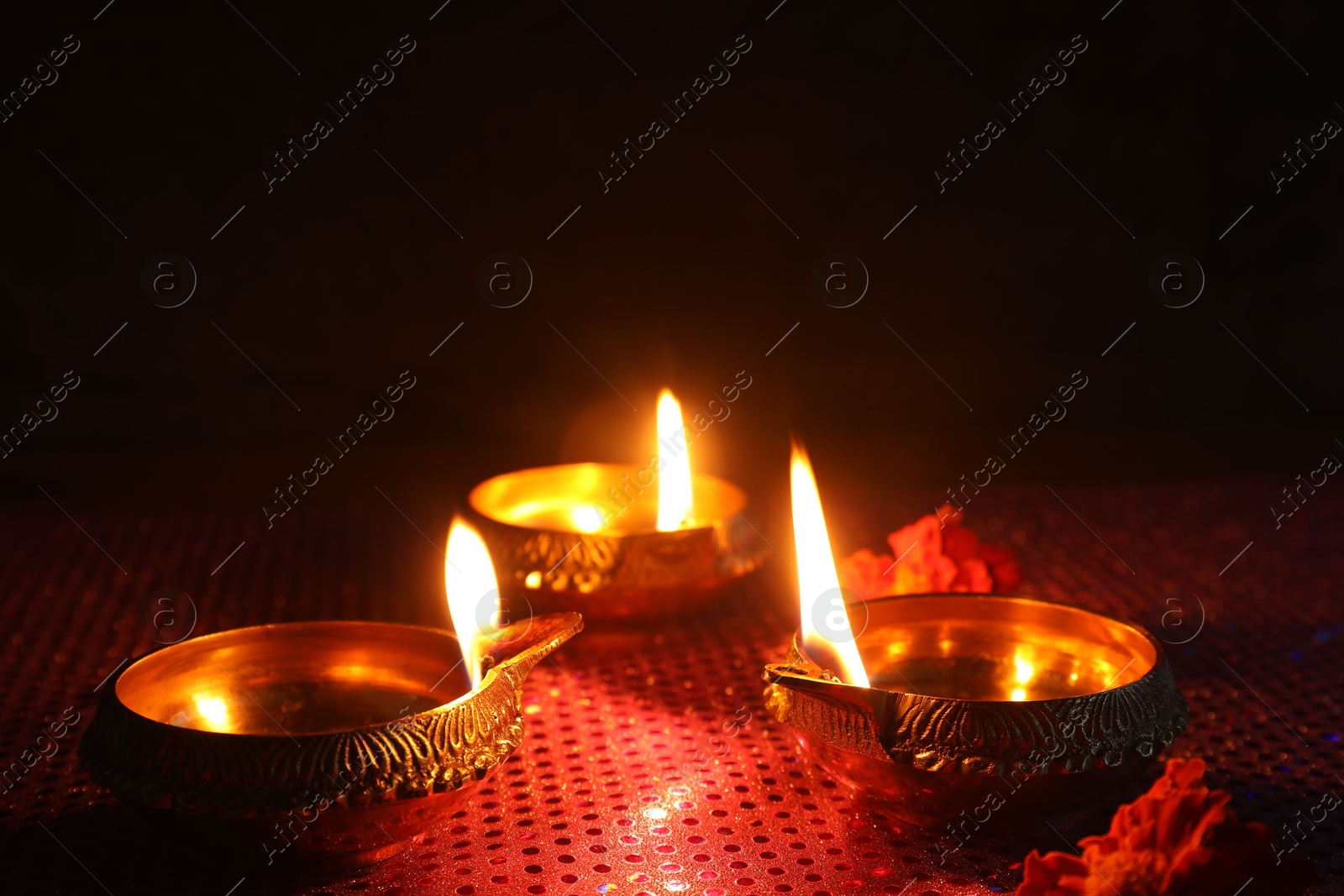 Photo of Diwali celebration. Diya lamps and beautiful flowers on dark background, closeup