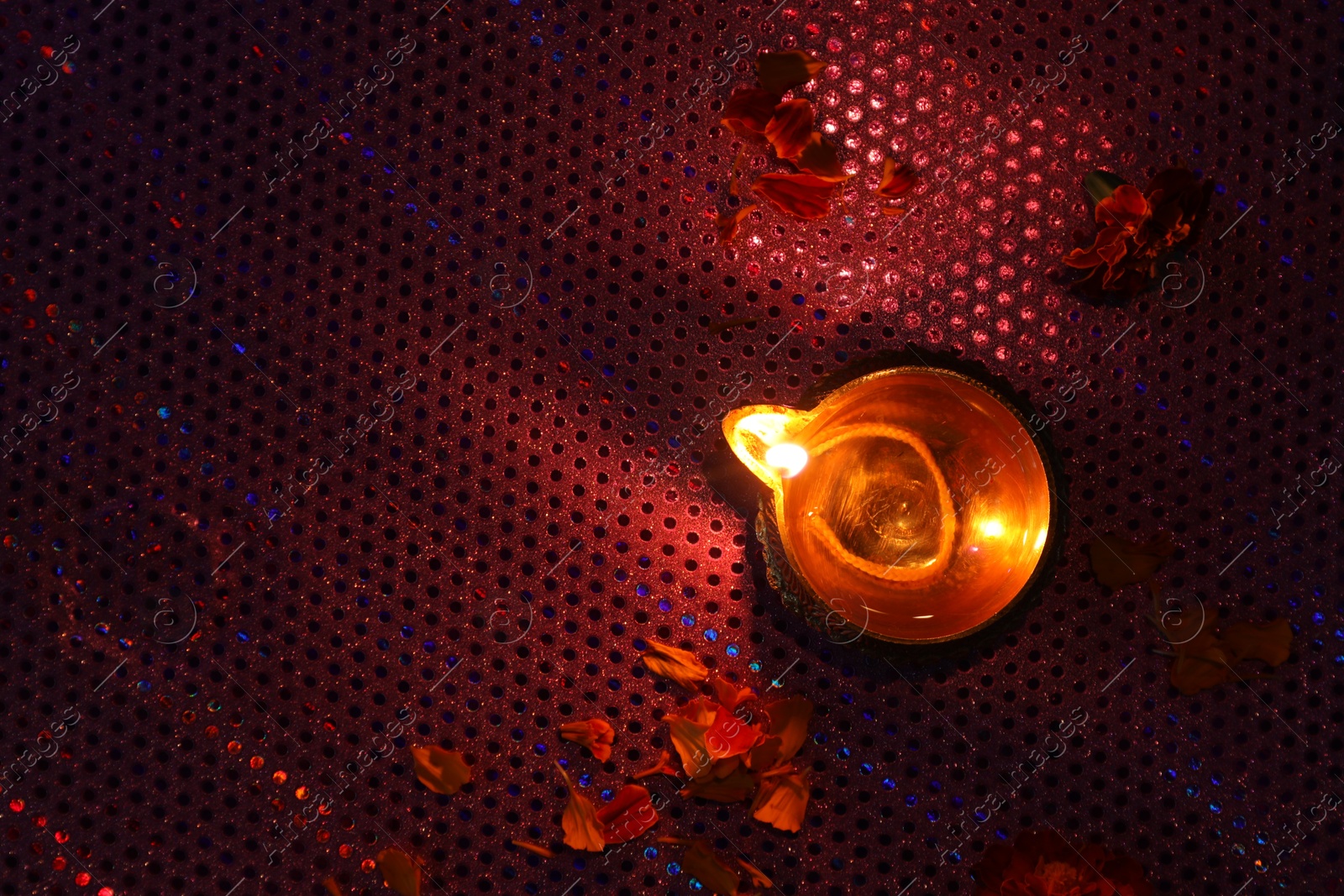 Photo of Diwali celebration. Diya lamp and beautiful flowers on dark background, top view. Space for text