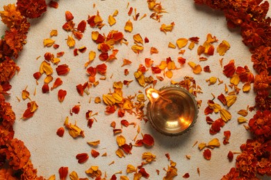 Photo of Diwali celebration. Diya lamp and beautiful flowers on light background, top view