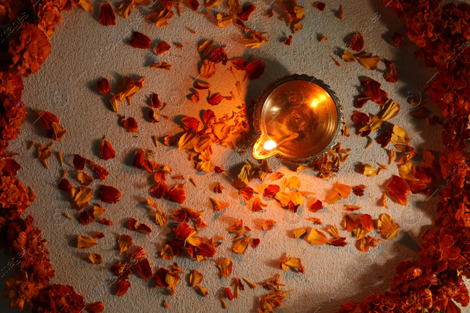 Photo of Diwali celebration. Diya lamp and beautiful flowers on light background, top view