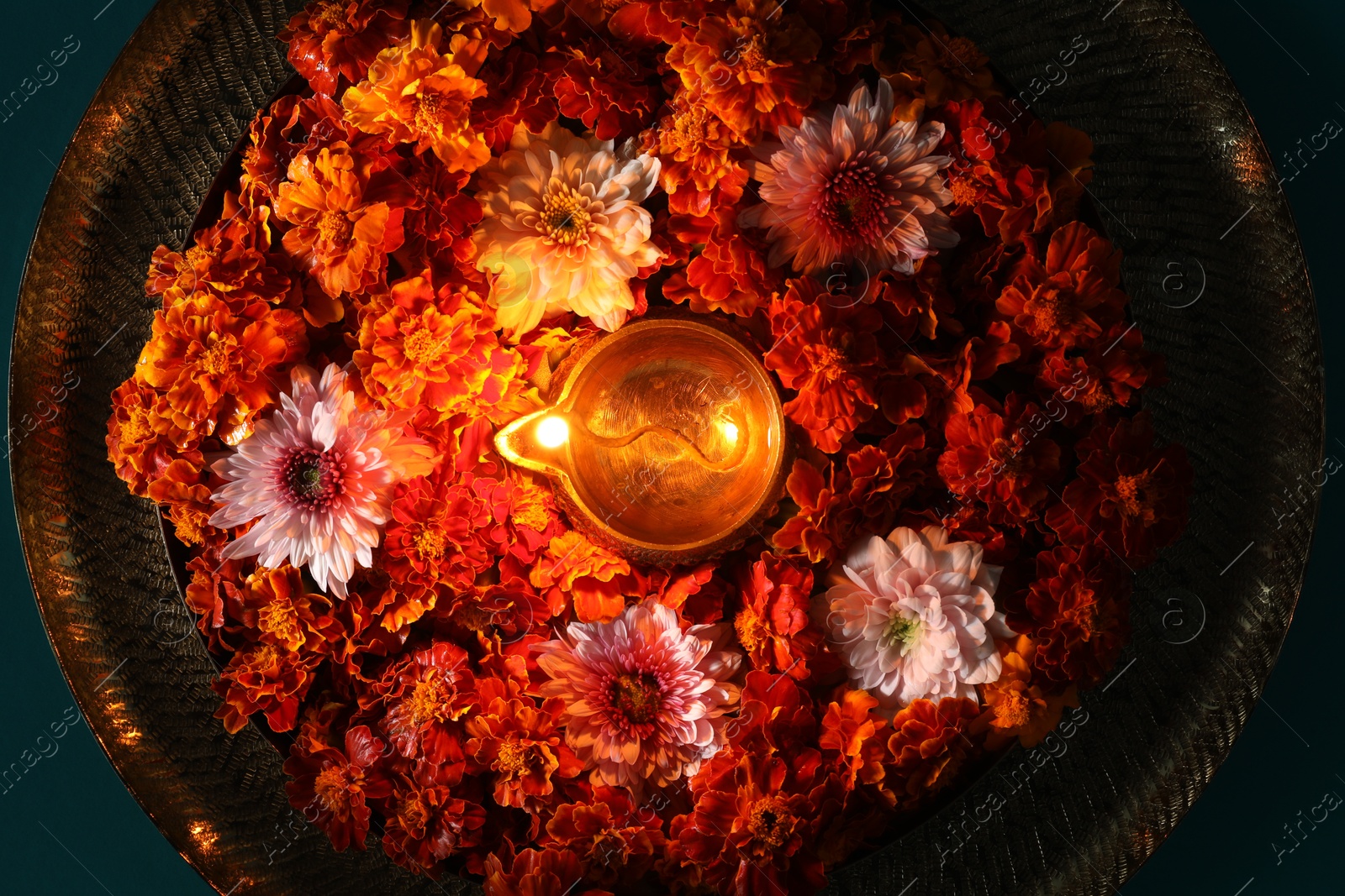 Photo of Diwali celebration. Diya lamp and beautiful flowers on turquoise background, top view