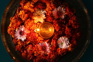 Photo of Diwali celebration. Diya lamp and beautiful flowers on turquoise background, top view