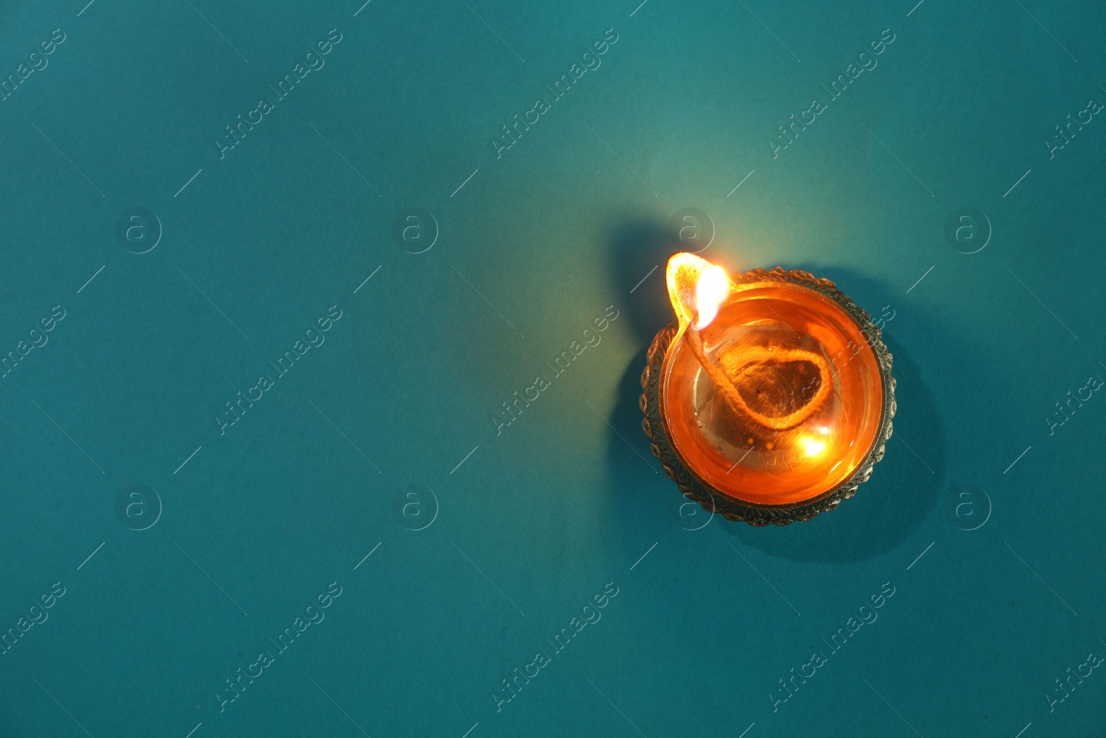 Photo of Diwali celebration. Diya lamp on teal background, top view. Space for text