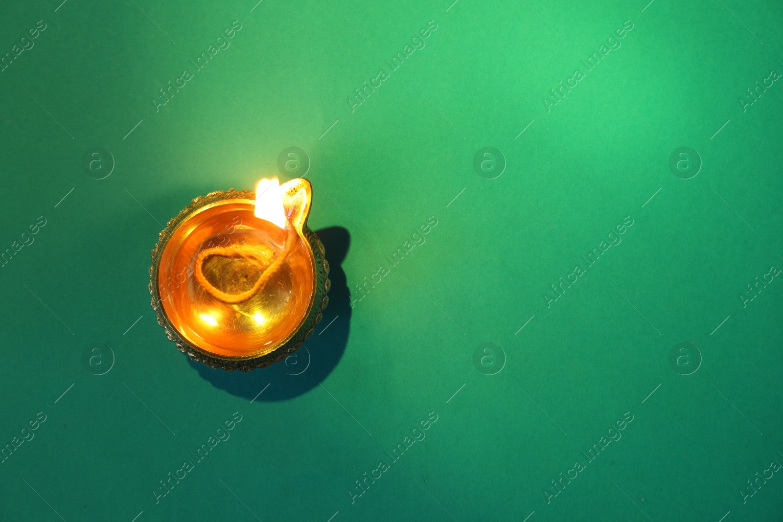 Photo of Diwali celebration. Diya lamp on green background, top view. Space for text