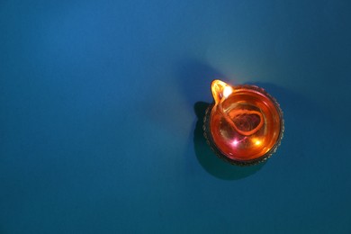 Photo of Diwali celebration. Diya lamp on blue background, top view. Space for text