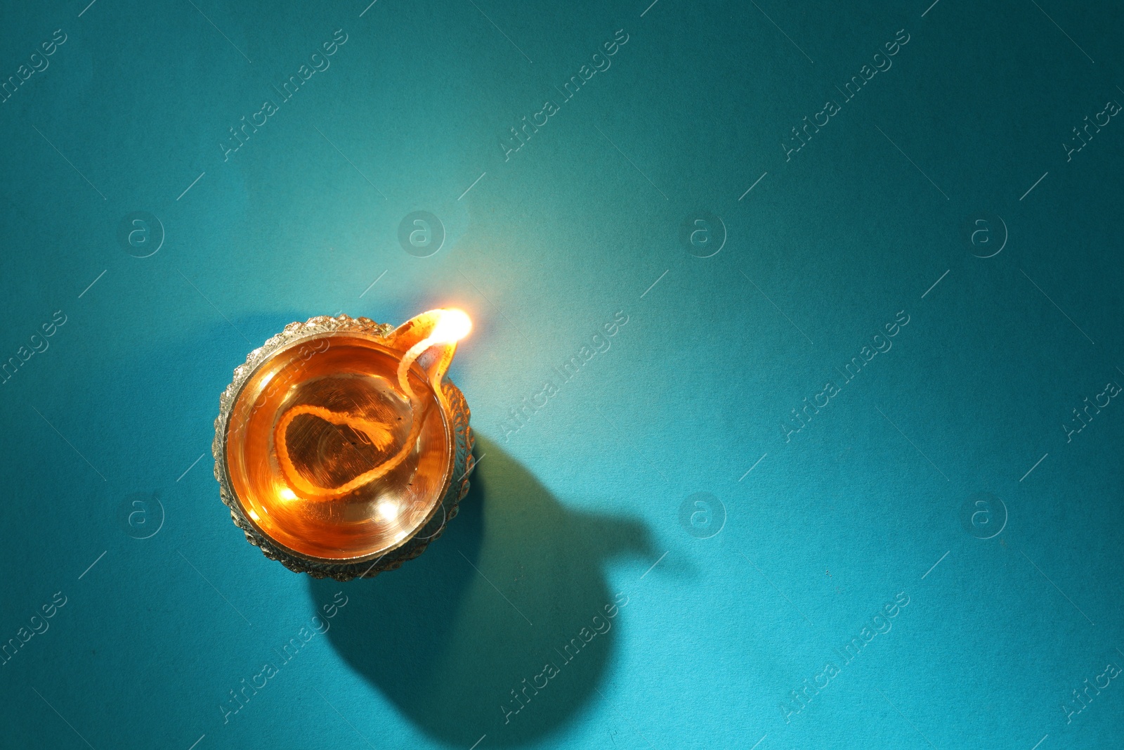 Photo of Diwali celebration. Diya lamp on teal background, top view. Space for text