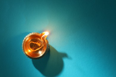 Photo of Diwali celebration. Diya lamp on teal background, top view. Space for text